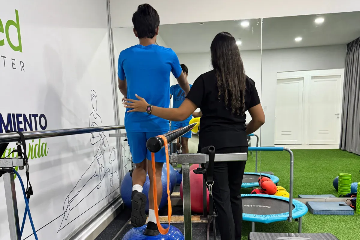 Paciente realizando un ejercicio de equilibrio sobre un BOSU con apoyo de una fisioterapeuta