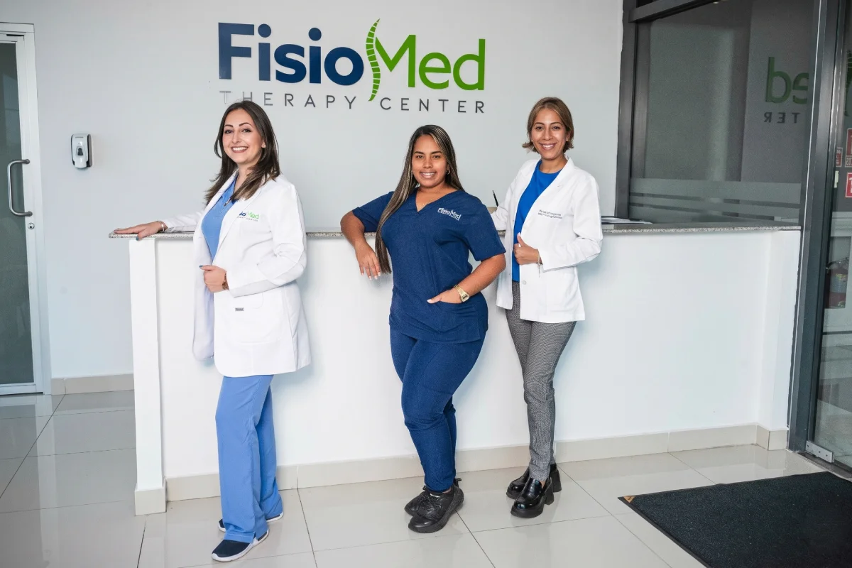 Tres profesionales de FisioMed frente al mostrador de recepción