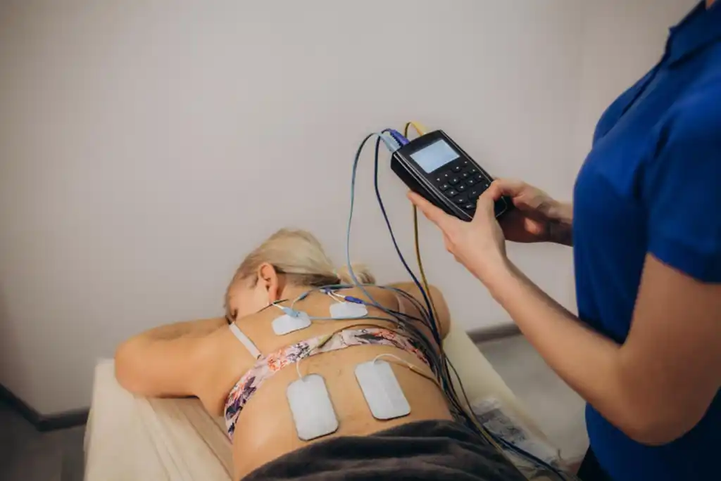 Paciente boca abajo con electrodos de electroterapia colocados en la espalda