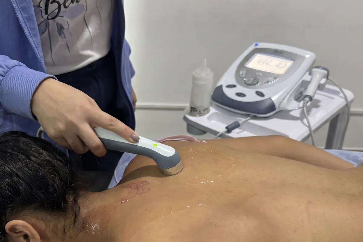 Fisioterapeuta aplicando radiofrecuencia térmica en la parte superior de la espalda de un paciente