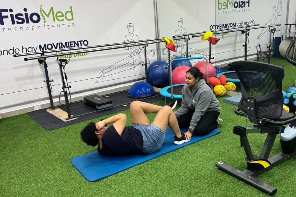 Paciente realizando un ejercicio de fortalecimiento del core con apoyo de una fisioterapeuta