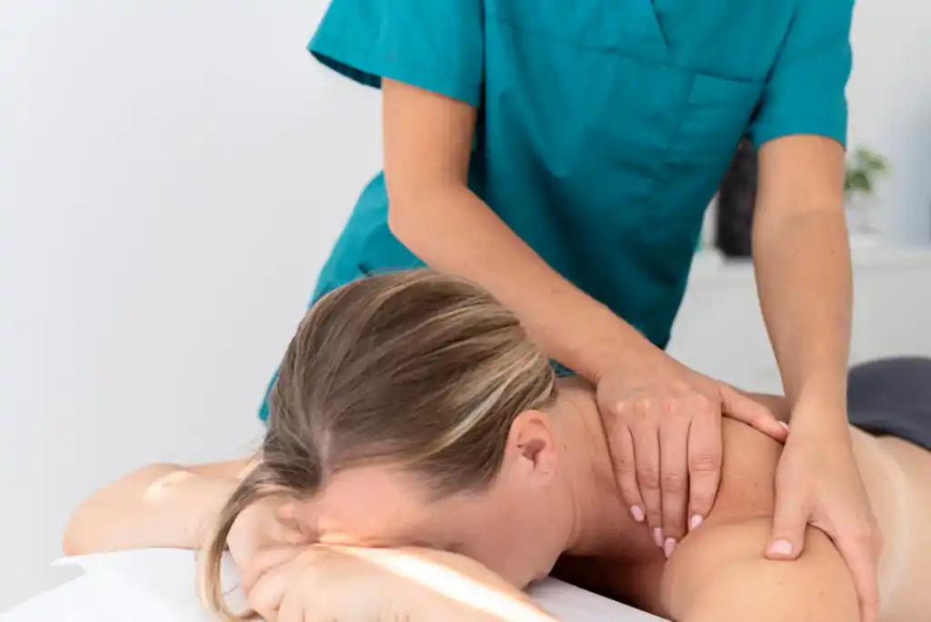Terapeuta realizando un masaje en la parte superior de la espalda de una paciente