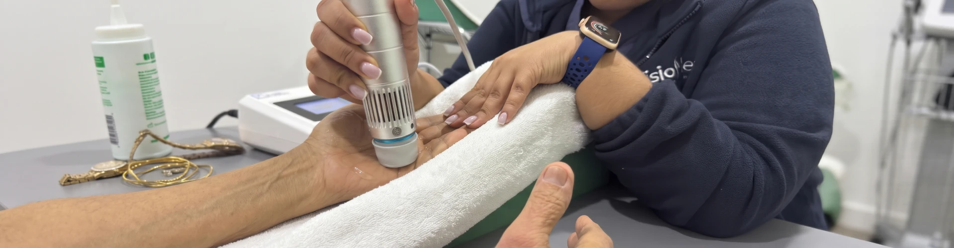 Profesional aplicando un dispositivo de ondas de choque en el dorso de una mano