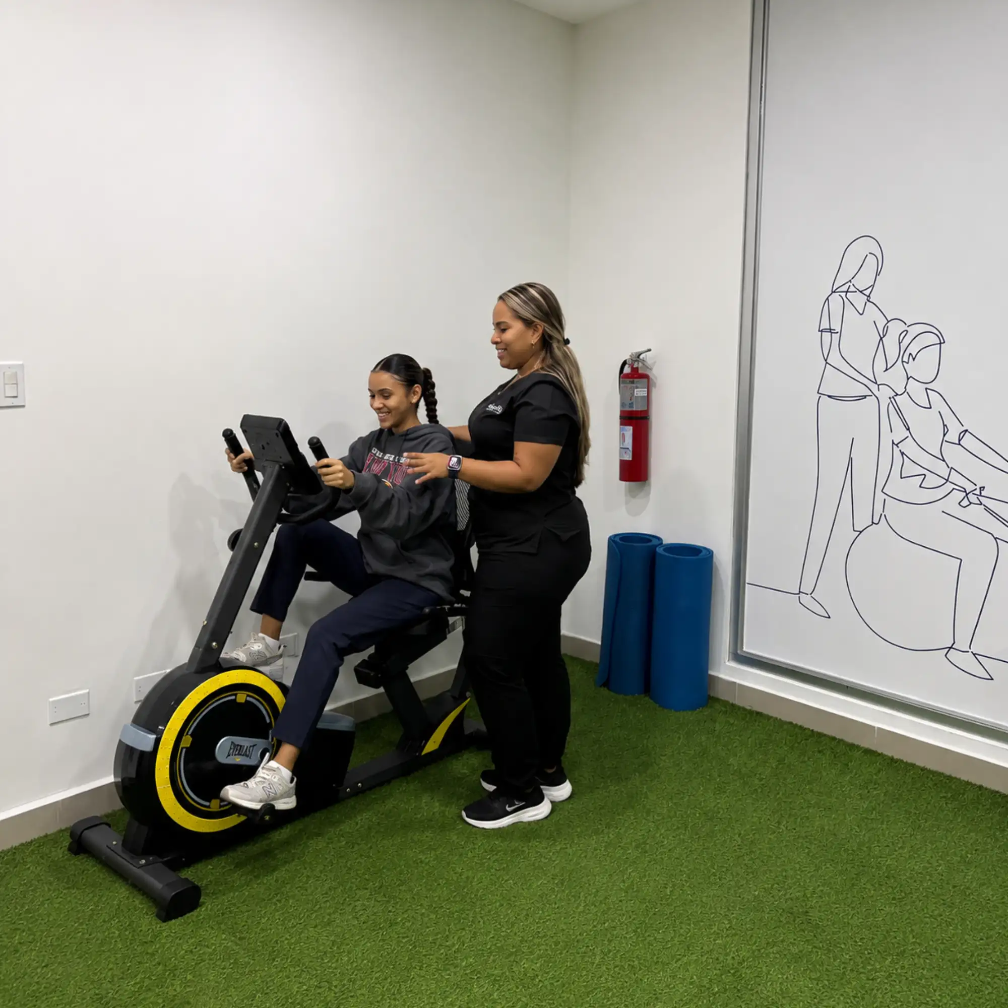 Paciente pedaleando en una bicicleta de rehabilitación con supervisión de una fisioterapeuta