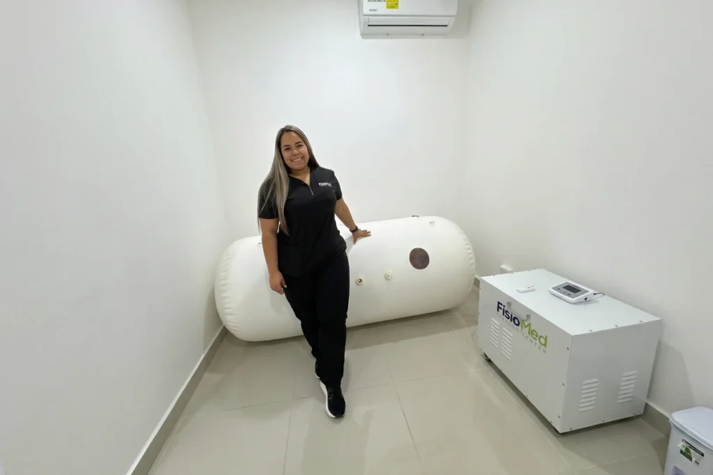 Profesional junto a una cámara hiperbárica suave blanca en FisioMed